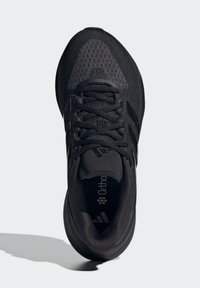 Chaussure de sport noire avec un dessus en mesh texturé, des superpositions synthétiques et trois bandes noires. Comprend un col rembourré et une semelle intérieure Ortholite.