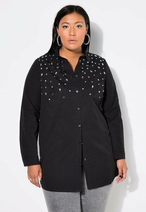 Camicia nera con bottone, caratterizzata da un davanti decorato con paillettes luccicanti di varie forme, maniche lunghe e una vestibilità rilassata.