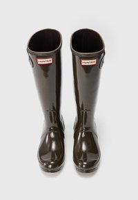 Botas altas de goma marrones con un acabado brillante, que presentan una punta redondeada, hardware de correas ajustables y etiquetas "HUNTER".