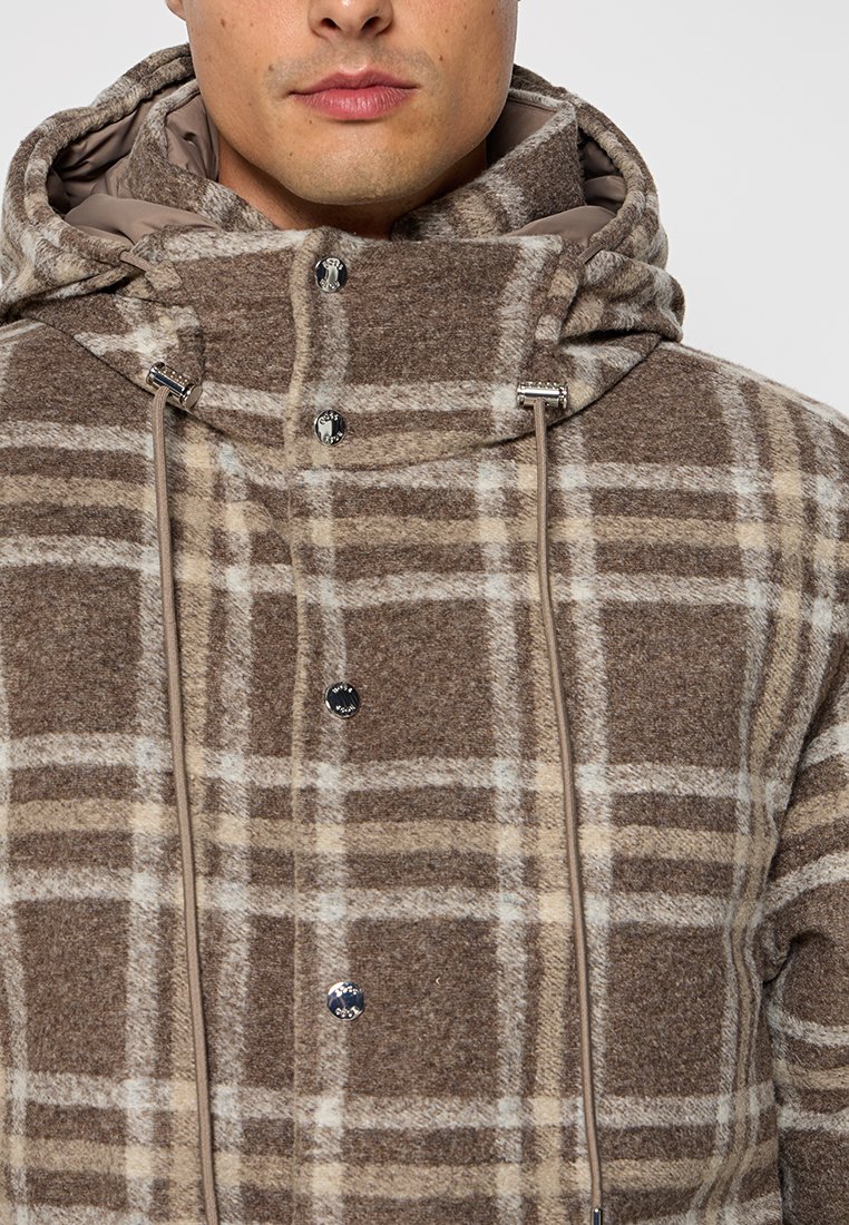 Veste à carreaux marron et beige avec une capuche, présentant une texture douce, des accents en matériel argenté et un ajustement par cordon.