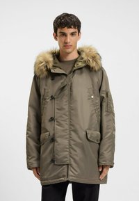 Beige parka-jack met een nepbont gevoerde capuchon, voorzien van grote klepzakken, een knoopsluiting en een soepele, gestructureerde buitenkant.