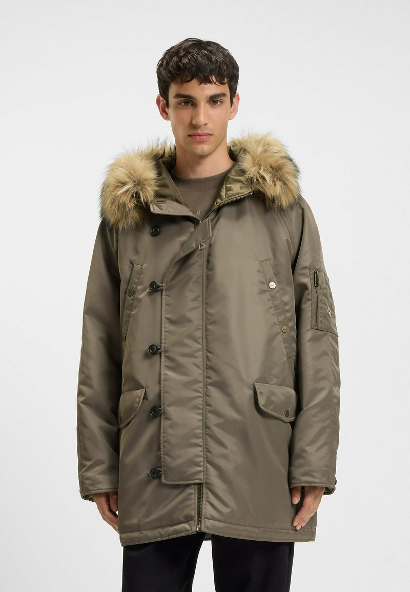 Beige parka-jakke med en hætte foret med faux pels, der har store klaplommer, knaplukning og en glat, struktureret overflade.