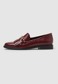 Bordeaux leren loafers met franjes, gouden hardware-accent en een lage zwarte rubberen hak. Glad textuur en klassiek ontwerp.