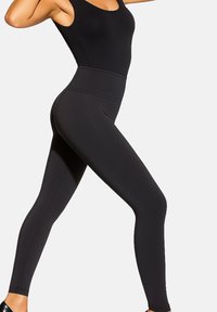 Czarne dopasowane legginsy z wysokim stanem, wykonane z elastycznego materiału. Gładka faktura i elegancki design, bez widocznych wzorów czy elementów metalowych.