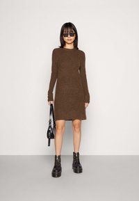 Brown knitted dress with long sleeves, round neckline, and a slightly flared hem, paired with black combat boots and a small black handbag.