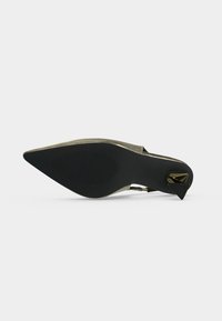Semelle d'une chaussure pointue en or métallique avec une semelle noire texturée et un petit talon géométrique noir et or.