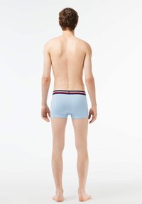Shorts en tronc bleu clair avec une ceinture rayée noire et rouge, design ajusté, texture lisse et sans motifs visibles.