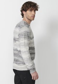Pulover tricotat cu dungi orizontale în nuanțe de gri și crem, guler rotund și manșete și tiv cu model în relief. Material texturat.