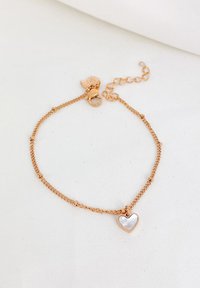 Bracciale in oro rosa con una catena fine, caratterizzato da piccoli accenti rotondi e un ciondolo a forma di cuore con superficie lucida. La chiusura include un estensore.