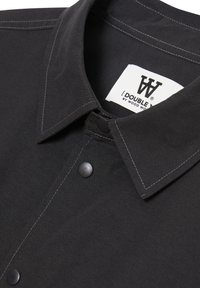 Black shirt featuring a classic collar, snap closure, and contrasting white stitching. Label reads "DOUBLE W by Wood Wood."