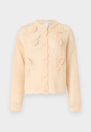 Knitted beige cardigan with a textured open weave, floral appliqués, scalloped hem, and central buttons. Lightweight and cropped design.