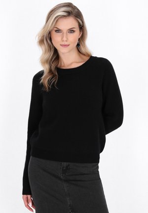 Maglione nero lavorato a maglia con scollo rotondo e maniche lunghe, abbinato a una gonna nera texturizzata. Tessuto morbido, vestibilità casual.