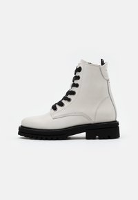Stivaletto bianco in pelle con lacci neri, superficie testurizzata, punta rinforzata e suola nera spessa con un motivo di battistrada robusto.