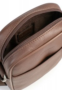 Borsa a tracolla in pelle marrone con esterno texturizzato, scomparto principale con zip e tasca frontale con una sottile etichetta logata.