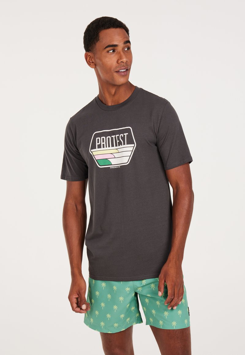 Grå kortærmet t-shirt med et multifarvet grafisk logo. Sammen med grønne badebukser med palmebladsmønster.