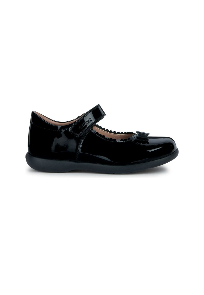 Zapato de charol negro estilo Mary Jane con punta redondeada, borde festoneado, acento de lazo y una correa de Velcro para un ajuste fácil.