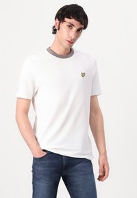 White cotton t-shirt with a round gray neckline. Features a small yellow butterfly logo on the left chest. Slim fit design.