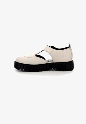 Chaussure en cuir blanc cassé avec découpes latérales ouvertes, semelle épaisse noire rainurée et bride sur le cou-de-pied, vue de côté sur fond blanc.