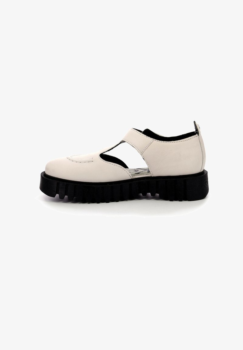 Chaussure en cuir blanc cassé avec découpes latérales ouvertes, semelle épaisse noire rainurée et bride sur le cou-de-pied, vue de côté sur fond blanc.