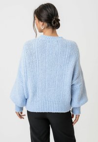 Ljust blå, oversized stickad tröja med ribbat mönster, sänkta axlar och vida ärmar, i ett mjukt och varmt material.