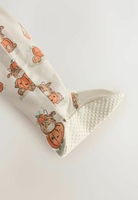 Śmietankowa skarpetka dziecięca z nadrukowanymi brązowymi zwierzętami trzymającymi dynie i białą, fakturowaną, antypoślizgową podeszwą.