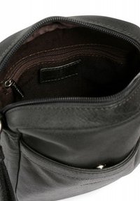 Interno di una borsa in pelle nera, con una tasca con zipper, rivestimento marrone e dettagli cuciti. Parte superiore aperta con superficie liscia e forma strutturata.