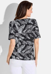 Zwart T-shirt met korte mouwen met een wit, ingewikkeld bloemen- en dierenpatroon, met een relaxte pasvorm en een ronde halslijn.
