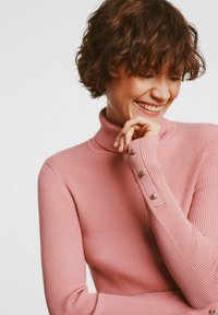 Różowy prążkowany sweter z wysokim kołnierzem, z długimi rękawami, z detalami w postaci guzików w kolorze złota na mankietach. Miękka tekstura i dopasowany krój.