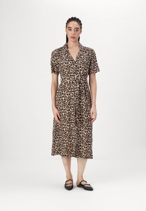 Robe à imprimé léopard, à manches courtes, avec un col, une ceinture à la taille et une coupe mi-longue flottante. Tissu doux avec une texture lisse. Chaussures plates noires.
