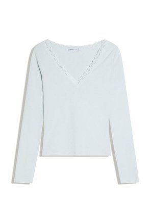 Svetlo modra majica z dolgimi rokavi in V-izrezom z okrasnim čipkastim robom, položena ravno na beli podlagi.