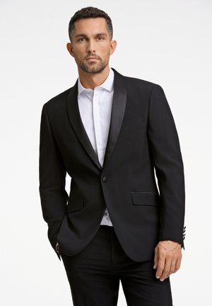 Zwart tuxedo jasje met satijnen revers, enkele knoopsluiting en zijzakken. Draag het over een witte blouse, met een verfijnd ontwerp.