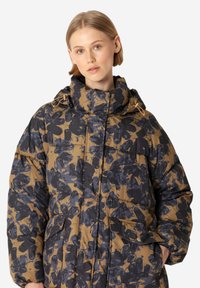 Abrigo de plumón acolchado con estampado floral en tonos marrón y azul oscuro, con un cuello alto, bolsillos grandes y capucha ajustable con cordón.
