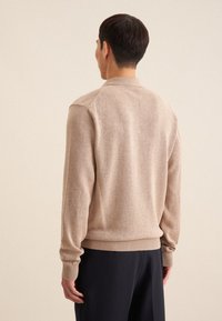 Beige Pullover aus leichtem, strukturiertem Strick, mit einem runden Kragen sowie gerippten Bündchen und Saum, entworfen für eine lockere Passform.