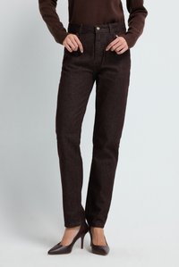 Pantalones de mezclilla marrones con corte recto, con cierre de botón y bolsillos, combinados con zapatos de tacón oscuro.