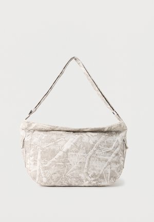 Šviesiai pilka petinė rankinė su abstrakčiu baltų šakų raštu ir reguliuojama dirželiu, eksponuojama prieš paprastą foną.