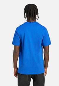 Plava pamučna majica sa kratkim rukavima i okruglim izrezom, s glatkom teksturom i opuštenim krojem.