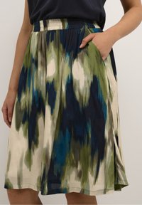 Une jupe midi multicolore avec un motif abstrait vert, bleu et crème, dotée d'une taille élastique et de poches latérales.