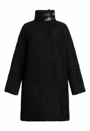 Manteau noir en tissu texturé, avec un col haut et deux accents de boucle au niveau du cou. Coupe loose avec des épaules落.