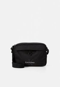 Black nylon crossbody bag with a zip closure, featuring a signature logo and an adjustable strap. Compact rectangular shape.