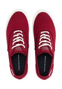 Rote Leinenschuhe mit weißen Schnürsenkeln und Gummisohlen. Sie haben eine runde Zehenpartie, ein kontrastierendes Logo auf der Innensohle und eine Nahtverarbeitung entlang der Seiten.