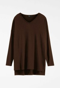 Smeđa bluza dugih rukava s V-izrezom, izrađena od mekanog materijala. Ima širok kroj sa bočnim prorezima i seže do bokova. Nema uzoraka ni ukrasnih elemenata.