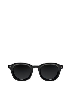 Schwarze Sonnenbrille mit einem klassischen, runden Rahmen-Design, ausgestattet mit dunklen Gläsern, glatter glänzender Oberfläche und metallischen Akzenten an den Schläfen.