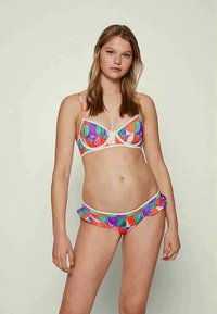 Conjunto de bikini colorido e estampado com um top estilo bralette com alças finas e parte de baixo com babados, feito de tecido elástico.