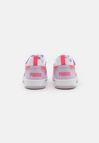 Baskets Puma avec des accents roses et violets, dotées d'un dessus blanc, de sangles Velcro et d'un branding bien visible au niveau du talon.