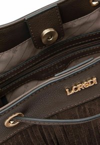 Interior de bolso de cuero marrón con diseño suave, herrajes dorados, bolsillos con cremallera y forro texturizado con detalle de logotipo.