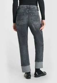 Jeans en denim gris foncé à coupe droite, avec des poignets repliés en gris clair et deux poches arrière avec un design subtil.