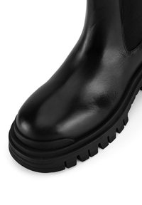 Bocanci din piele neagră până la glezne, cu un upper neted, panouri elastice pe laterale și o talpă robustă din cauciuc cu adâncimi pentru tracțiune.