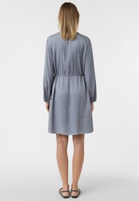 Szara sukienka do kolan z długimi rękawami i sznurkiem w talii. Gładka tekstura i minimalistyczny design, z delikatnym detalem na plecach.