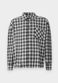 Black and white checkered long-sleeve shirt in soft fabric, featuring a button-down front and chest pocket. Collared design with relaxed fit.