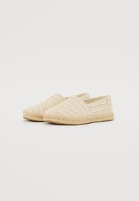 Espadrilles beiges avec un tissu rayé blanc et rose clair, design à bout fermé et semelle en jute tissée, dotées d'inserts élastiques pour un enfilage facile.
